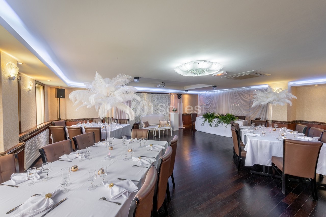 Salle de réception élégante avec tables dressées, décorations blanches et éclairage tamisé.