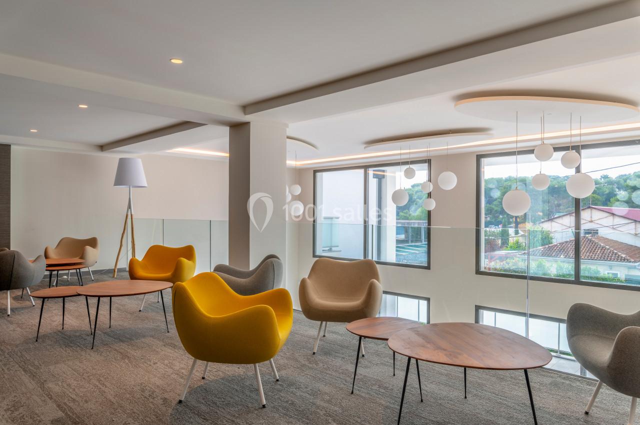 Espace lumineux avec des fauteuils modernes, des tables basses en bois et des suspensions sphériques près de grandes…