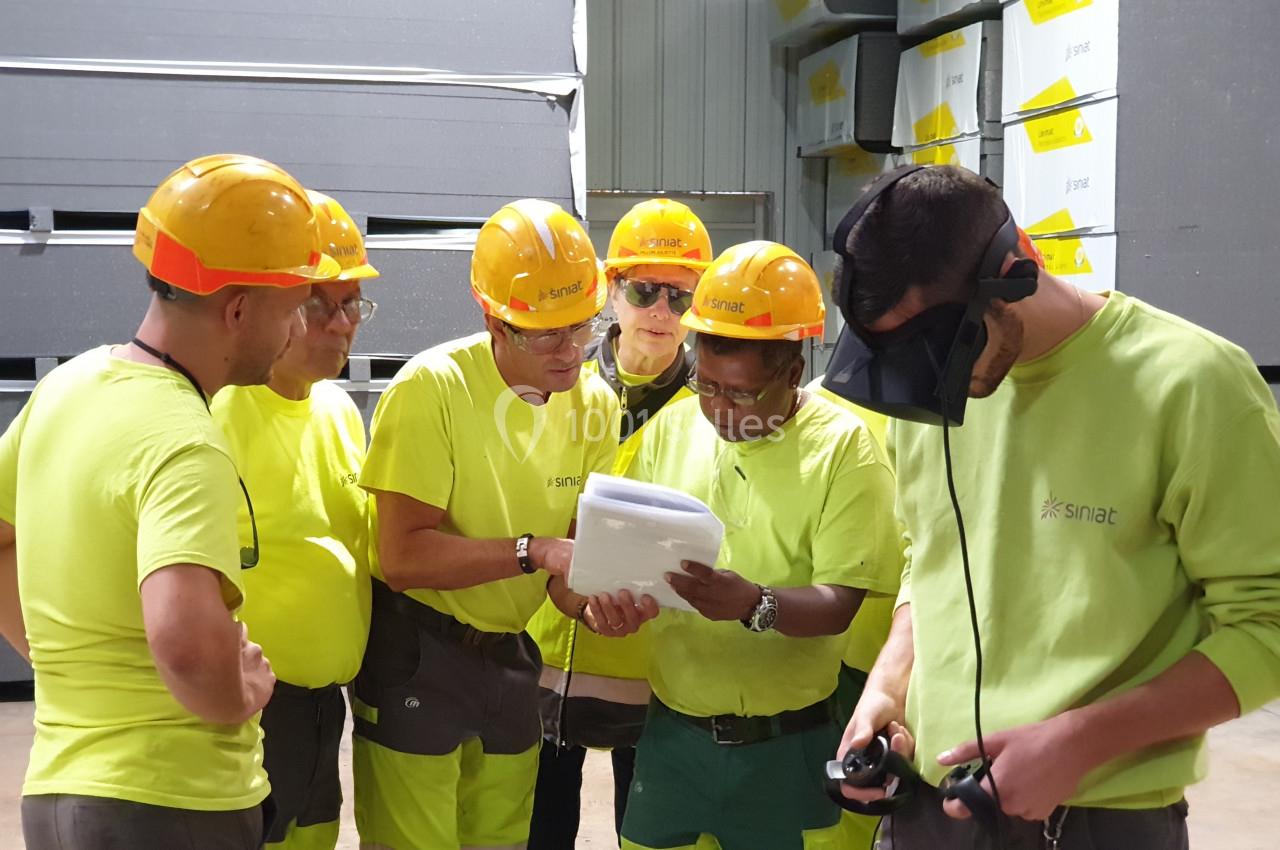 Des ouvriers en tenue de sécurité consultent un document dans un entrepôt industriel.