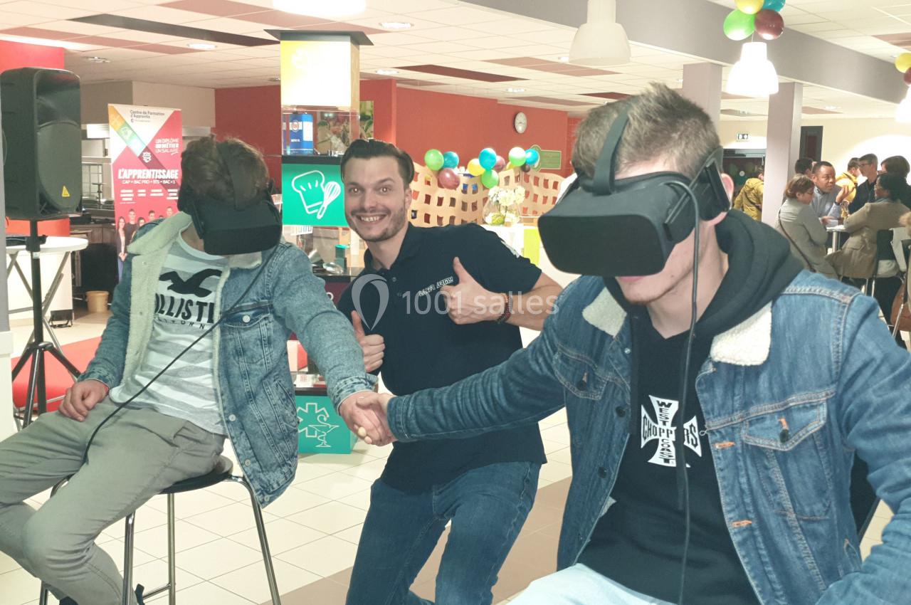 Deux personnes portant des casques de réalité virtuelle se tiennent la main dans un espace intérieur animé.