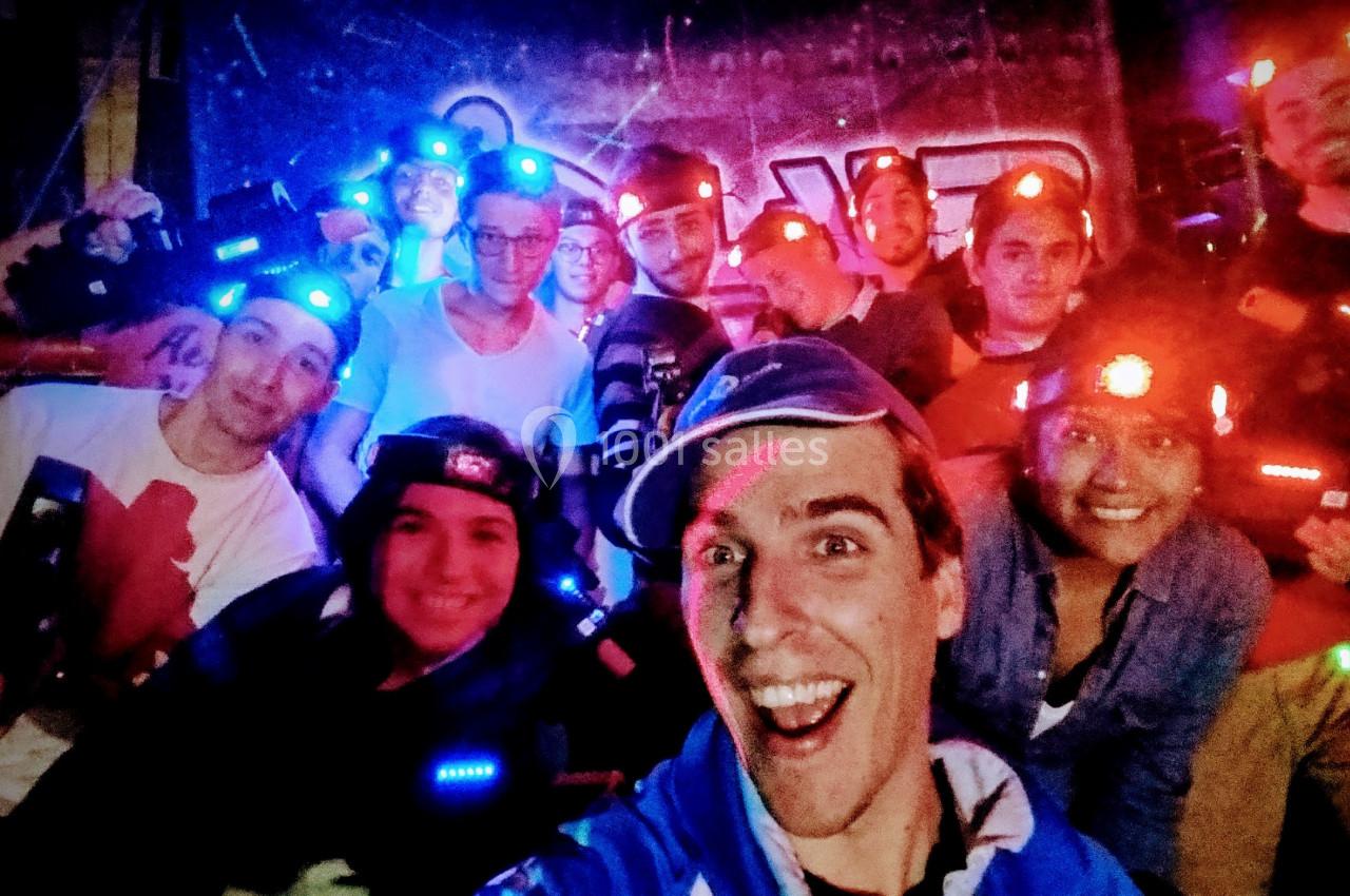 Un groupe de personnes souriantes portant des équipements lumineux dans un environnement sombre, probablement lors d'une…