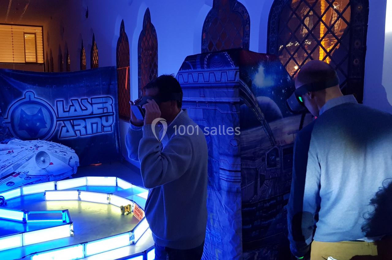 Deux personnes participent à une activité immersive de réalité virtuelle dans un décor futuriste éclairé.