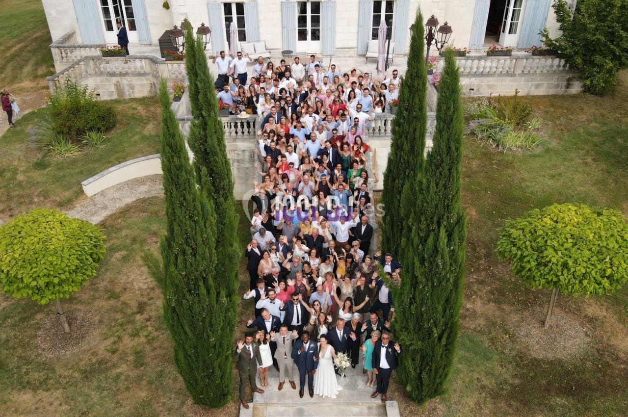 Groupe de personnes posant sur les marches d'un bâtiment élégant entouré de cyprès et de verdure.