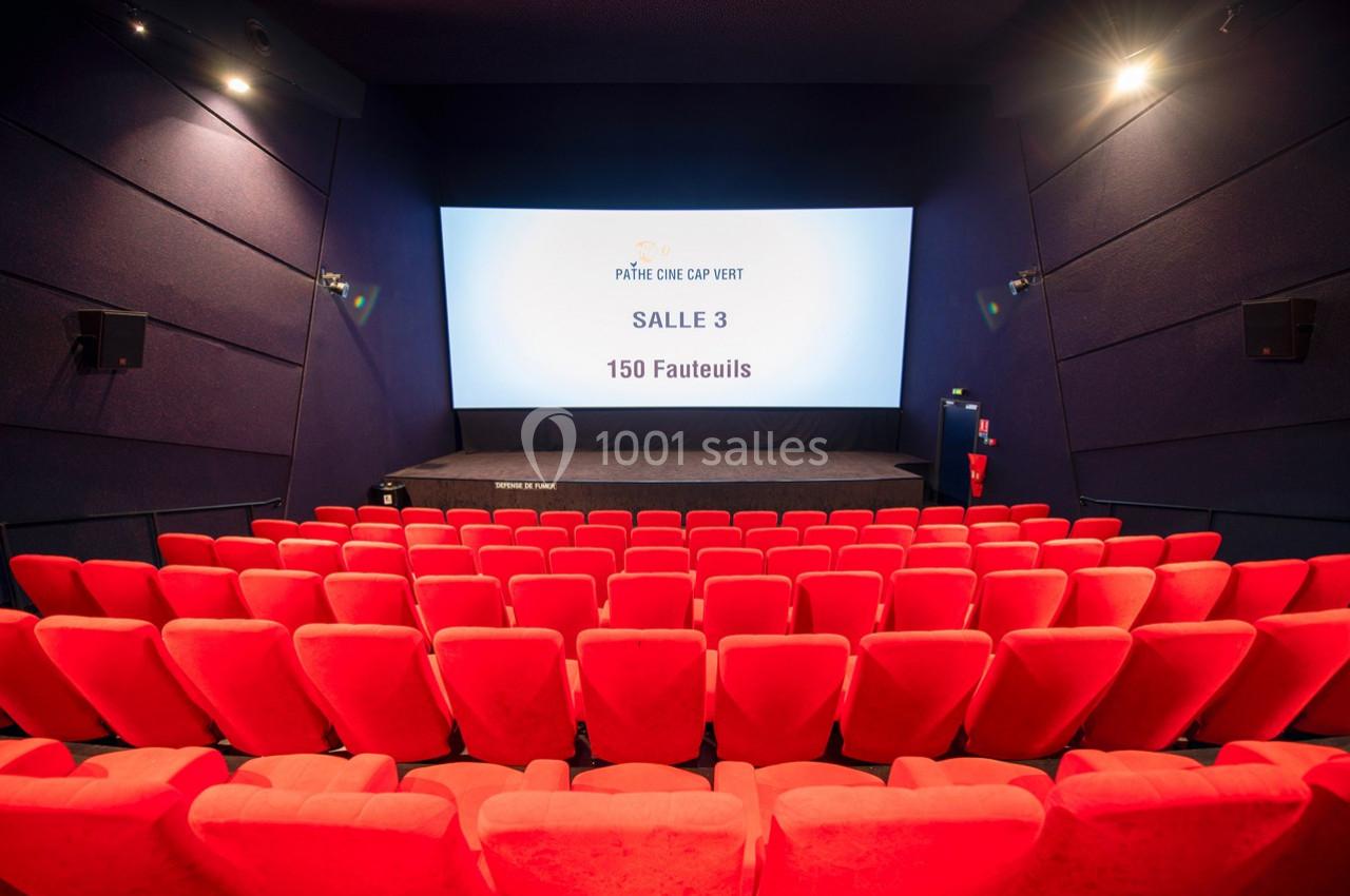 Salle de cinéma vide avec des rangées de fauteuils rouges, écran affichant ’Salle 3 - 150 fauteuils’.