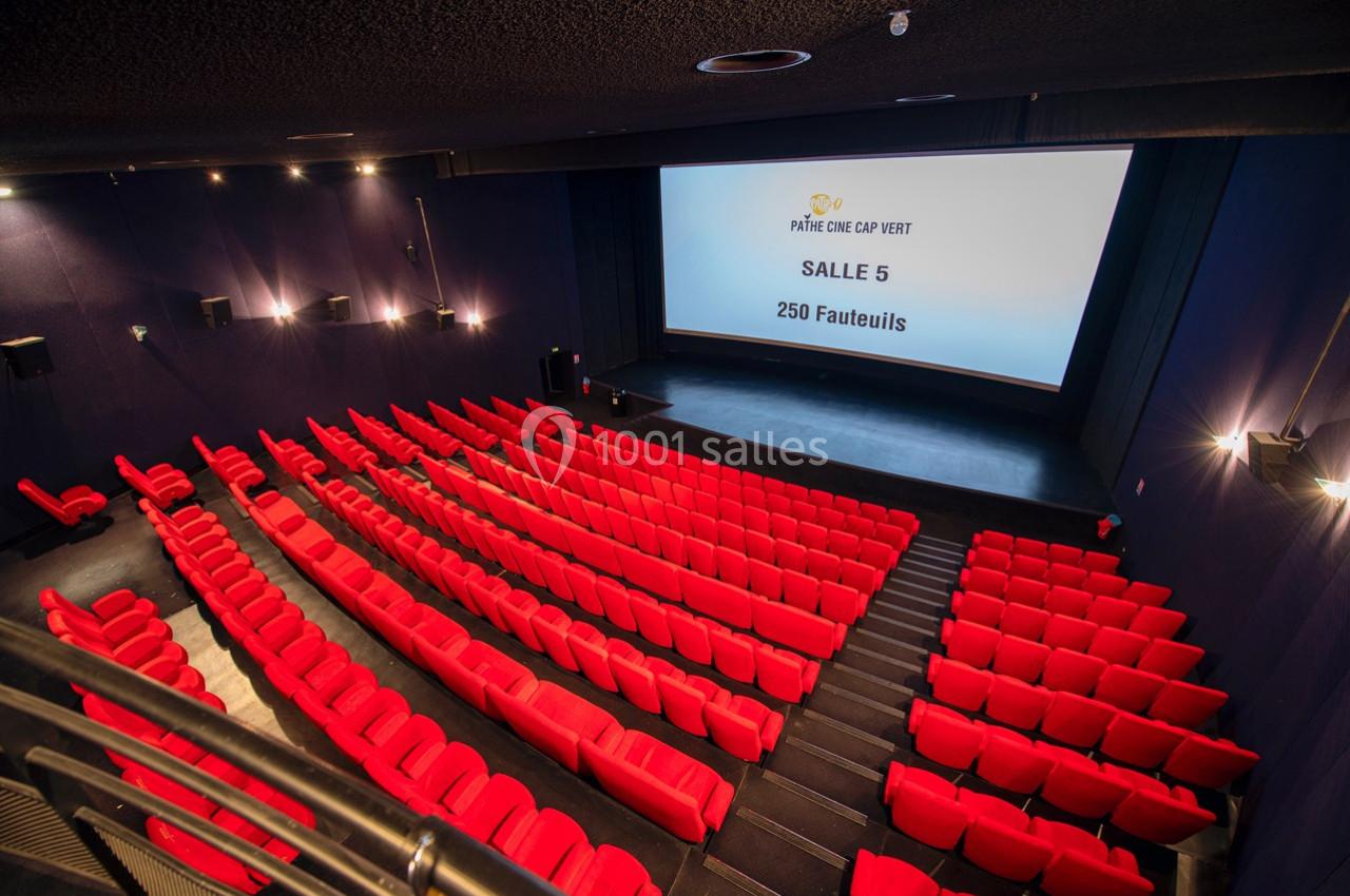 Salle de cinéma avec des rangées de fauteuils rouges et un écran affichant ’Salle 5, 250 fauteuils’.