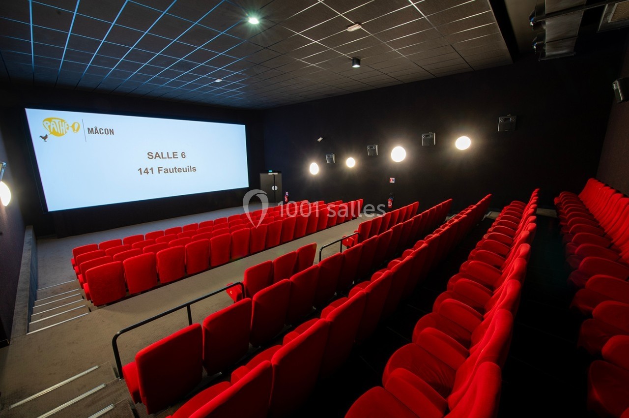 Salle de cinéma vide avec des rangées de fauteuils rouges, écran blanc affichant ’Salle 6, 141 fauteuils’.