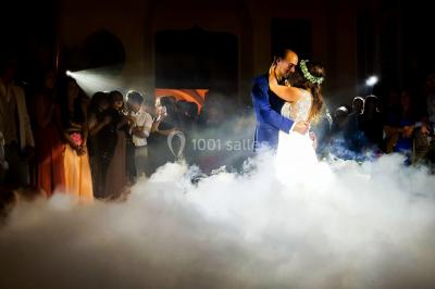 Un couple danse au milieu d'une piste entourée de fumée, tandis qu'un musicien joue du saxophone en avant-plan.