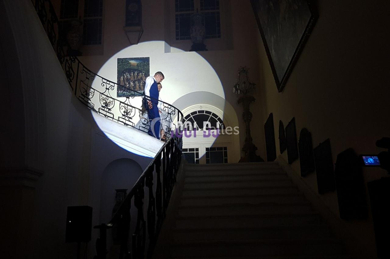 Un homme descend un escalier éclairé par un projecteur dans un intérieur sombre et élégant.