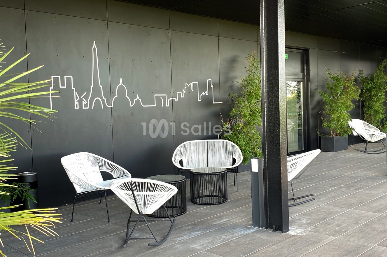 Terrasse moderne avec mobilier en rotin, plantes en pot et fresque murale représentant une skyline urbaine.