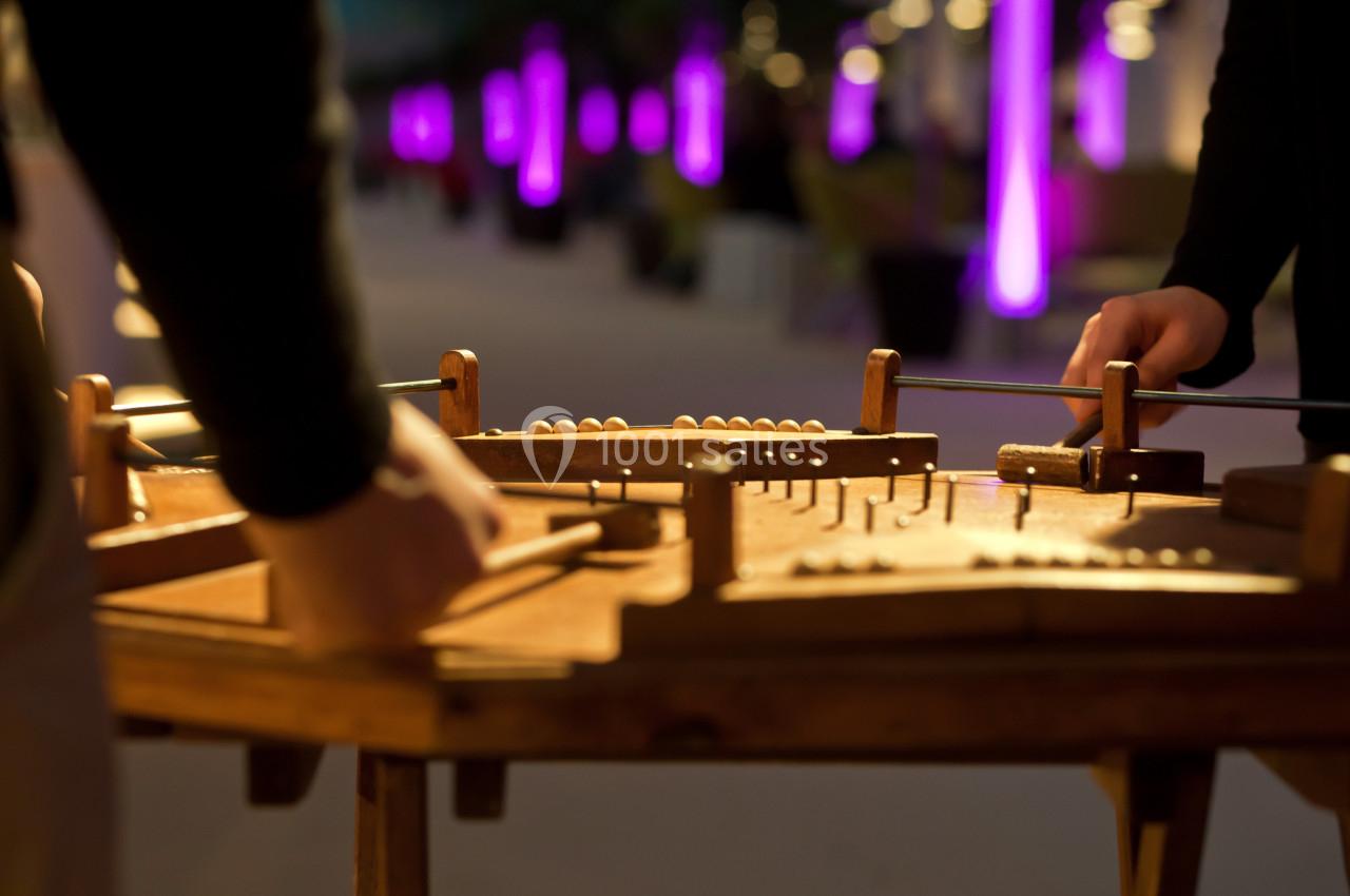 Personnes jouant d'un instrument de musique à cordes sur une table en bois, éclairées par des lumières violettes en arrière…