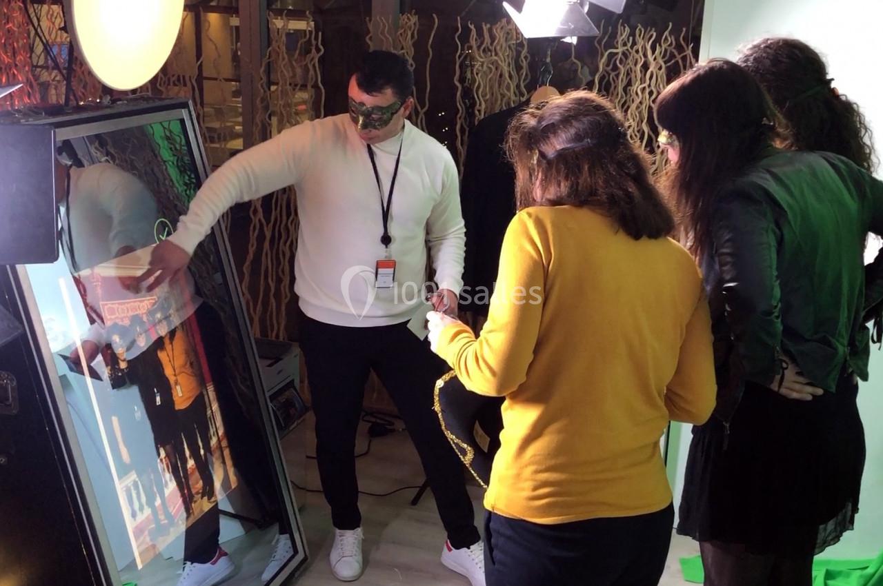 Un homme interagit avec un miroir interactif entouré de trois personnes dans un espace éclairé.