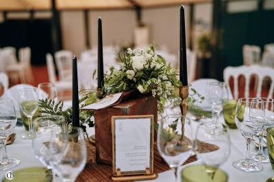 Salle de réception éclairée la nuit, avec des tables dressées visibles à travers les baies vitrées.
