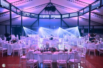 Salle de réception éclairée la nuit, avec des tables dressées visibles à travers les baies vitrées.