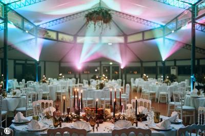 Salle de réception éclairée la nuit, avec des tables dressées visibles à travers les baies vitrées.