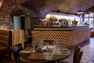Miniature Location salle Mons-en-Baroeul (Nord) - Fort de Mons #12 Salle de restaurant avec murs en briques, bar éclairé en arrière-plan et table dressée au premier plan.
