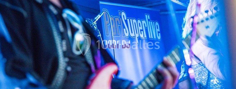 Un musicien joue de la guitare électrique sur une scène éclairée, avec une bannière en arrière-plan.