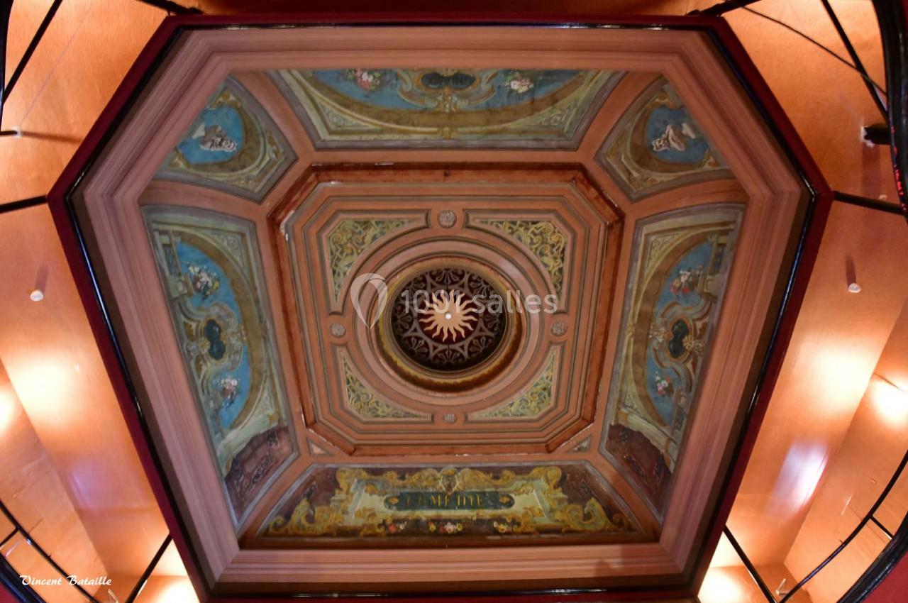 Plafond hexagonal décoré de fresques colorées et d'un motif central en forme de soleil entouré d'ornements.