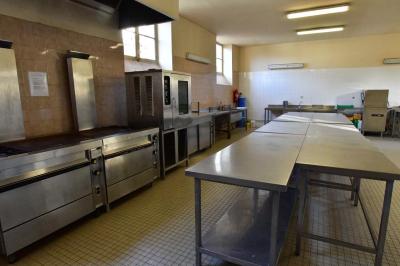 Salle spacieuse avec parquet en bois, grandes baies vitrées et quelques plantes en arrière-plan.