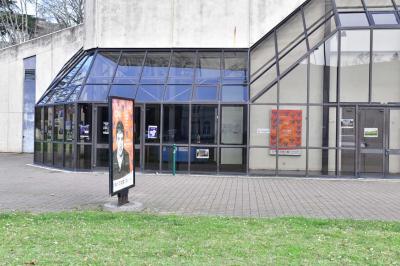 Salle spacieuse avec parquet en bois, grandes baies vitrées et quelques plantes en arrière-plan.