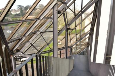 Salle spacieuse avec parquet en bois, grandes baies vitrées et quelques plantes en arrière-plan.