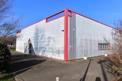 Deux personnes observent une maquette sous vitrine dans une salle avec des plantes et des panneaux d'exposition.