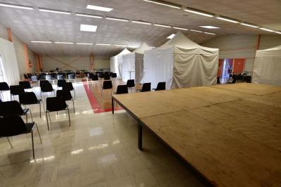 Deux personnes observent une maquette sous vitrine dans une salle avec des plantes et des panneaux d'exposition.