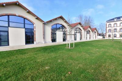 Bâtiment avec toit en tuiles et arcades, entouré d'une clôture métallique ornée de motifs végétaux.