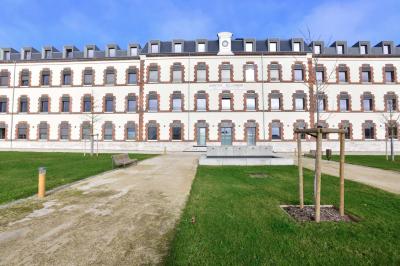 Bâtiment avec toit en tuiles et arcades, entouré d'une clôture métallique ornée de motifs végétaux.