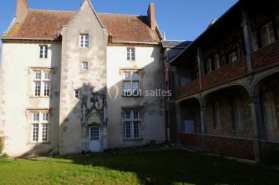 Atelier d'artiste lumineux avec tables de travail, matériel de peinture, étagères et une toile en cours.