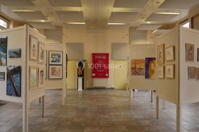 Entrée vitrée d'un bâtiment avec des plantes en pot et des peintures accrochées aux murs.