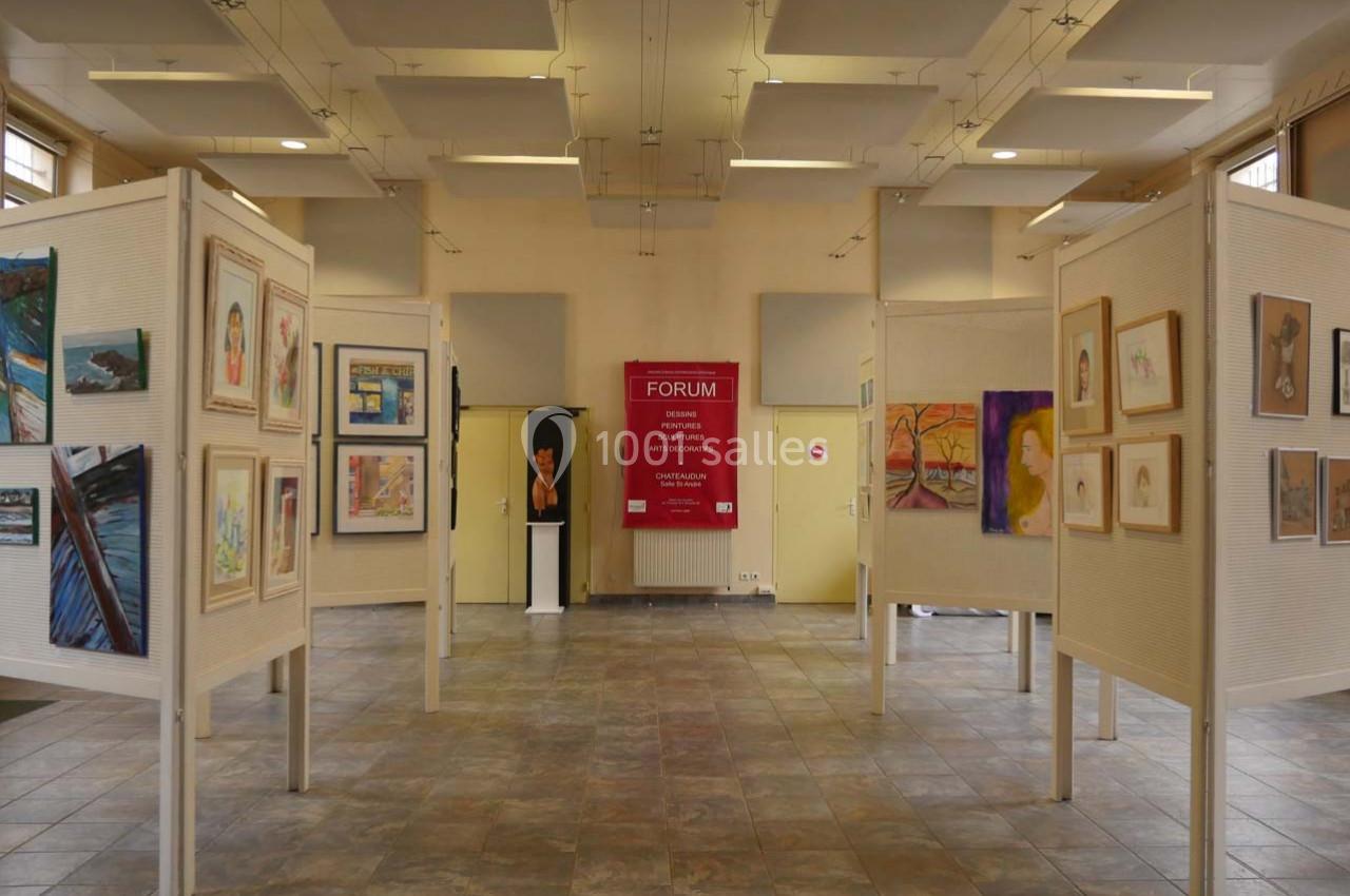 Salle d'exposition avec des panneaux affichant des peintures et dessins variés, éclairée par une lumière naturelle.