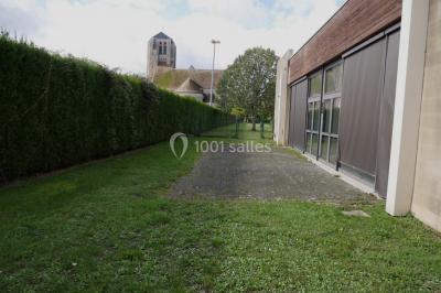 Cuisine professionnelle avec plan de travail en inox, cuisinière, évier, hotte et équipements muraux dans un espace carrelé.