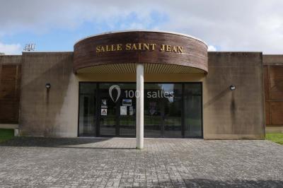 Cuisine professionnelle avec plan de travail en inox, cuisinière, évier, hotte et équipements muraux dans un espace carrelé.