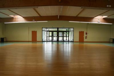 Cuisine professionnelle avec plan de travail en inox, cuisinière, évier, hotte et équipements muraux dans un espace carrelé.