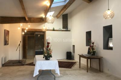 Des personnes assises sur des tapis et des chaises dans une salle lumineuse avec un tableau et des rideaux.