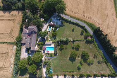 Des personnes assises sur des tapis et des chaises dans une salle lumineuse avec un tableau et des rideaux.