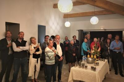 Des personnes assises sur des tapis et des chaises dans une salle lumineuse avec un tableau et des rideaux.