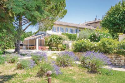 Des personnes assises sur des tapis et des chaises dans une salle lumineuse avec un tableau et des rideaux.