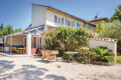 Des personnes assises sur des tapis et des chaises dans une salle lumineuse avec un tableau et des rideaux.