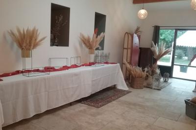 Des personnes assises sur des tapis et des chaises dans une salle lumineuse avec un tableau et des rideaux.