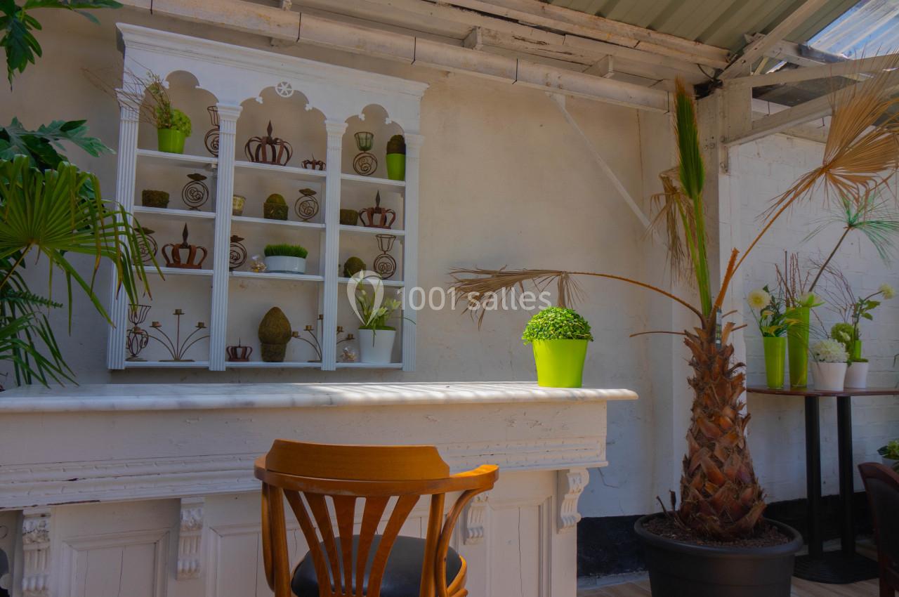 Étagère blanche décorative avec plantes et objets, devant un comptoir en marbre, entourée de végétation.