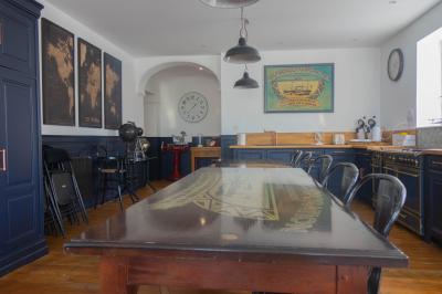 Miniature Location salle Cassel (Nord) - Le Haut Cassel #25 Salon avec fauteuils en cuir, table basse en bois, plante verte, bibliothèque et tableau sur un mur lambrissé.