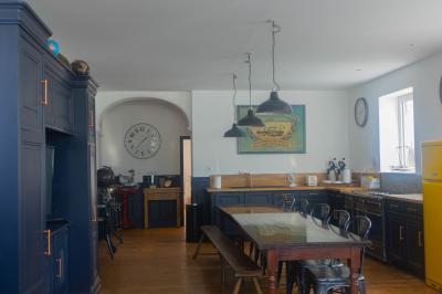 Miniature Location salle Cassel (Nord) - Le Haut Cassel #26 Salon avec fauteuils en cuir, table basse en bois, plante verte, bibliothèque et tableau sur un mur lambrissé.