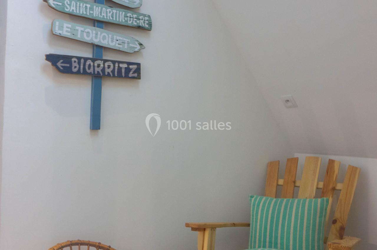 Deux fauteuils en bois, dont un avec coussin rayé, près d'un mur décoré de panneaux directionnels colorés.