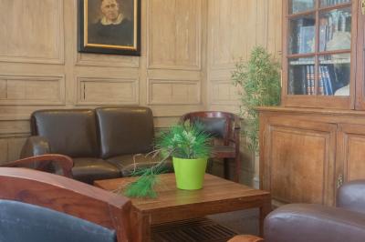 Miniature Location salle Cassel (Nord) - Le Haut Cassel #45 Salon avec fauteuils en cuir, table basse en bois, plante verte, bibliothèque et tableau sur un mur lambrissé.
