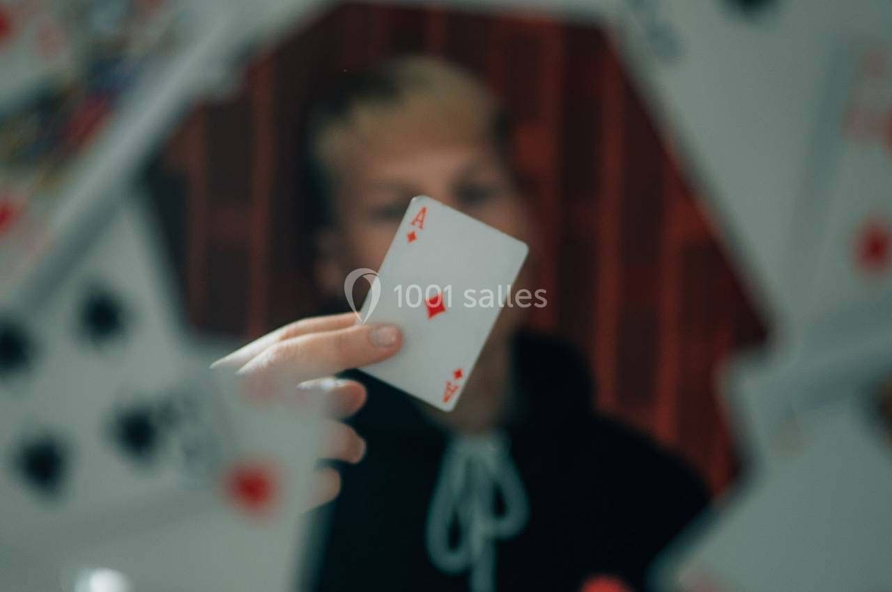 Une personne tenant une carte As de carreau, entourée de cartes floues en avant-plan.