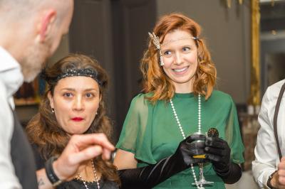 Un groupe de personnes assises et debout, riant et échangeant lors d'un moment convivial en extérieur.