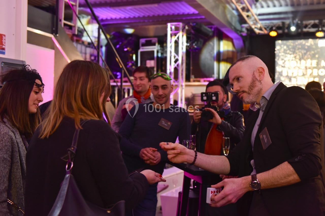 Un magicien réalise un tour de cartes devant un petit groupe de personnes lors d'un événement en intérieur.