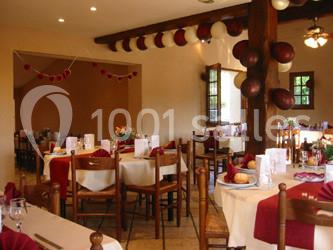 Salle de réception décorée avec des ballons rouges et blancs, tables dressées avec nappes et serviettes assorties.
