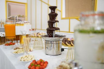 Table dressée avec une assiette blanche, un cadeau doré, une serviette beige nouée et des macarons en décoration.